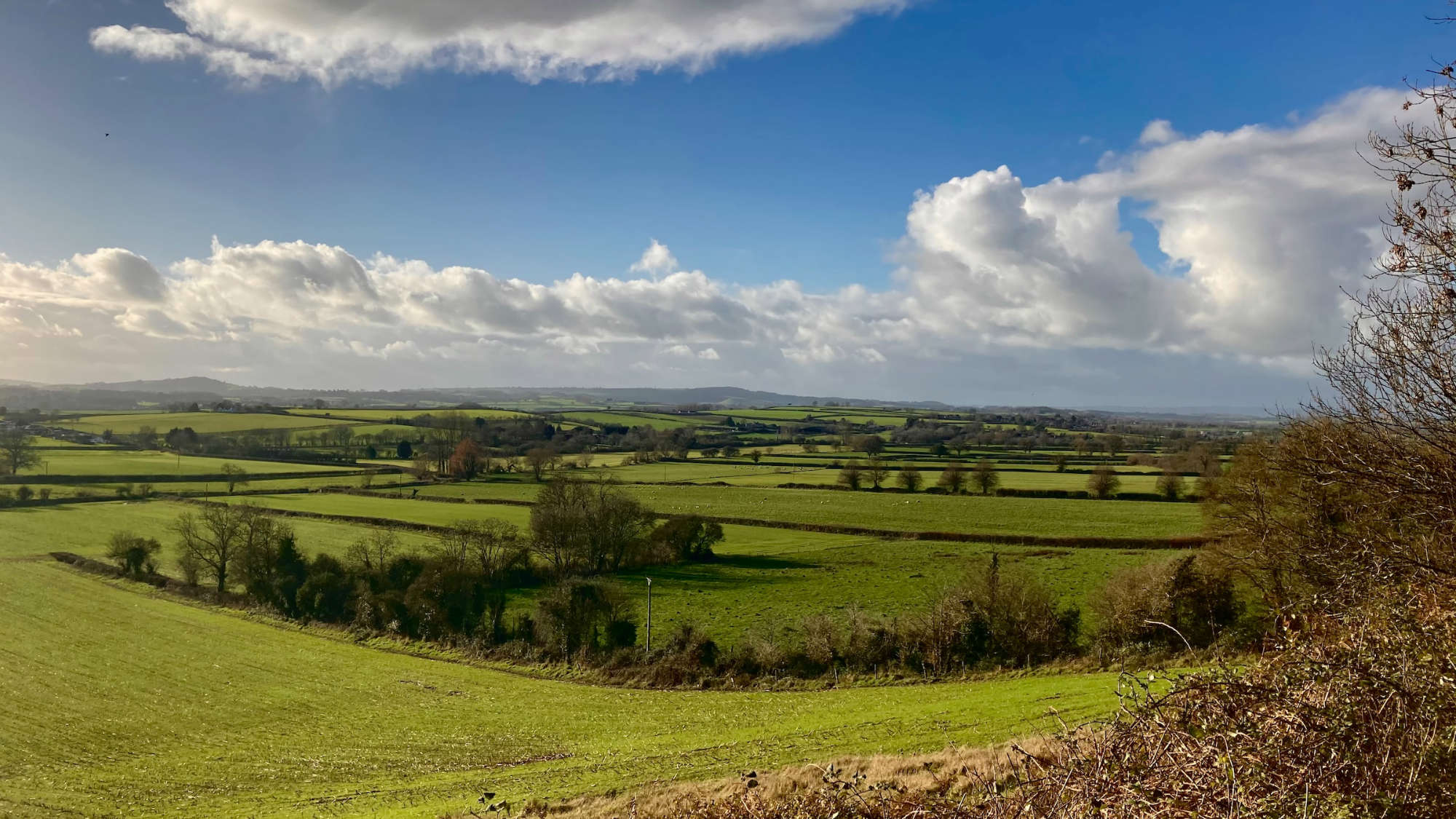 A landscape of green fields and cloudy skies